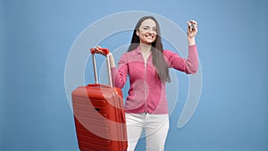 Young woman holding a suitcase showing the keys isolated over blue background