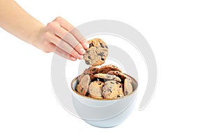 Young woman holding tasty chocolate chip cookie over bowl on white background