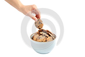 Young woman holding tasty chocolate chip cookie over bowl on white background