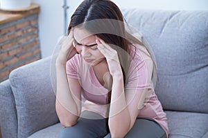 Young woman are holding their hands to the head in pain on the sofa at home. Young women have severe headaches from migraines