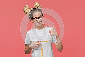 Young woman holding thumb up being glad measuring her breast.