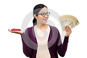 Young woman holding a toy car and Indian currency