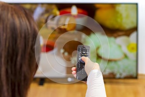 Young woman holding tv remote and surfing programs