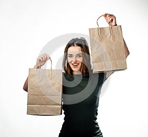 Young woman is holding two grocery shopping bags on white background. Paper bag near face. Isolated background.