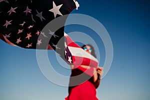 young woman holding United States flag outdoors at sunset. Independence day in America, 4th July concept
