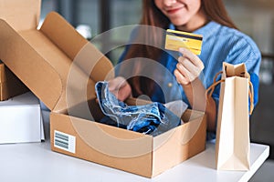 A young woman holding and using credit card for online shopping with shopping bag and postal parcel box of