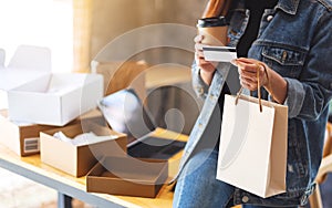 A young woman holding and using credit card for online shopping with tablet pc and postal parcel box on the table