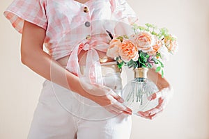 Young woman holding vase with bouquet of fresh flowers. Floral arrangement with orange roses Lady of Shallott