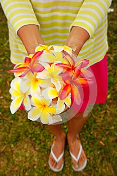 Young woman holding white and pink plumeria flowers