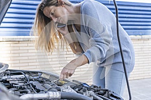 Young woman holding a wrench to repair broken car, while is phone calling to remote help assistance