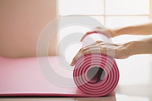 Young woman holding a yoga mat in exercise class
