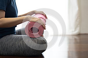 Young woman holding a yoga mat in exercise class for a sport and healthy concept