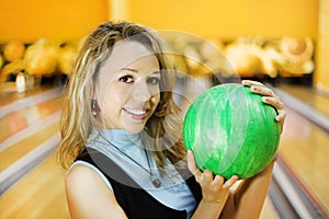 Young woman holds ball in bowling club