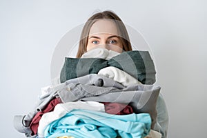 Young woman holds full of clean linen, housewife looks tired after doing laundry, works about house.