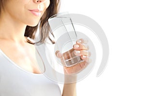 A young woman holds a glass of water in her hand and is about to drink it. White background. Copy Space