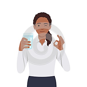 Young woman holds a glass of water in his hand with ok sign and wink. The concept of water balance and health