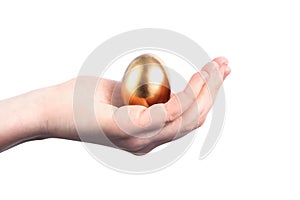 Young woman holds a golden chicken egg in her hand