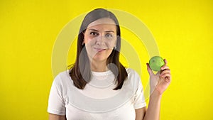 A young woman holds a green apple in her hand. A girl in a white T-shirt smiles and shows a super sign. The concept of