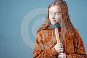 a young woman holds a hammer with both hands and thinks what to do next