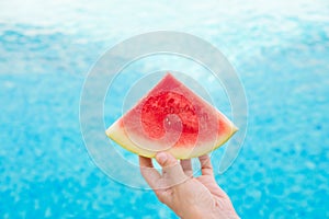 Young Woman Holds in Hand Wedge Slice of Juicy Watermelon by Swimming Pool. Blue water. Sunlight. Vacation Relaxation