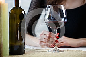 A young woman holds in her hand a glass of wine on a blind date. Close up