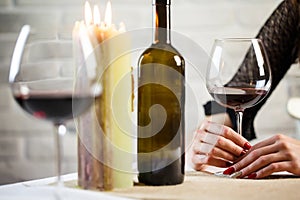 A young woman holds in her hand a glass of wine on a blind date. Two wineglass on the table. Close up