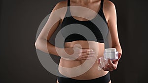 A young woman holds a jar of cream in her hands and applies cream to skin. She is fat after pregnancy baby birth.