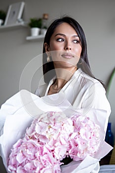 Young woman holds light tender pink hydrangea bouquet