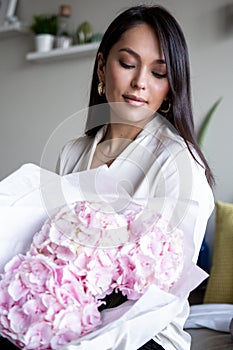 Young woman holds light tender pink hydrangea bouquet