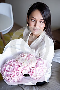 Young woman holds light tender pink hydrangea bouquet