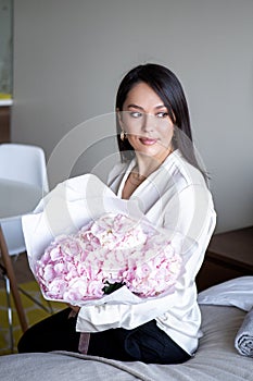 Young woman holds light tender pink hydrangea bouquet