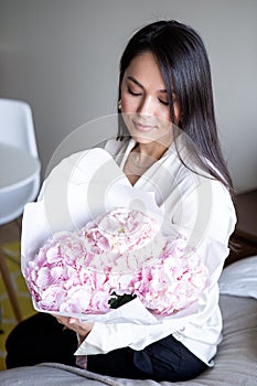 Young woman holds light tender pink hydrangea bouquet