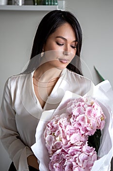 Young woman holds light tender pink hydrangea bouquet