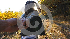 Young woman holds male hand and jogs along path near woodland. Follow me shot of happy girl leads her boyfriend along