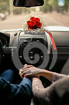 A young woman holds a man& x27;s hand in her hands in a car