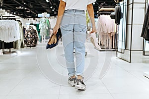 Young woman holds many shoes in clothing store