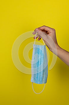 A young woman holds a medical face mask in her hand. Health care concept