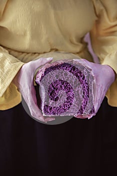 A young woman holds a piece of organic bread that made of red carrot, close up