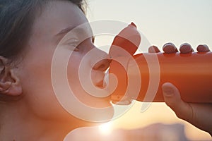 Young woman holds a reusable steel stainless water bottle and drinks