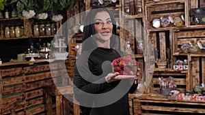 A young woman holds ripe strawberries in a health food grocery store.