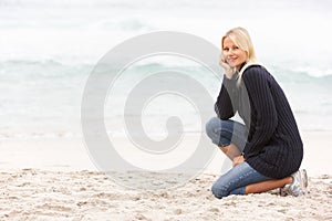 Young Woman On Holiday Kneeling On Beach