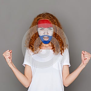 Young woman with Holland flag painted on her face