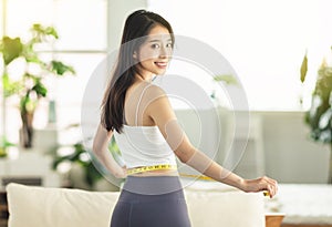 A young woman at home, holding a measuring ruler while dancing, turning around, very satisfied with her posture, very happy to