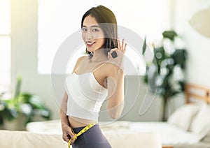 A young woman at home holding a measuring ruler while dancing, turning around, very satisfied with her posture, very happy to