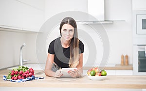 Young woman in home kitchen with tablet