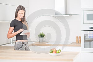Young woman in home kitchen with tablet