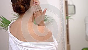 young woman, at home, lavishes her shoulder with moisturizing cream in the bathroom,