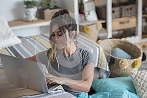 Young woman at home laying on the floor studying with laptop computer and sofa desktop - happy lifestyle female