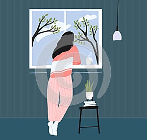 Young woman at home longing at window. Spring landscape outside, blue sky with clouds and trees. Cozy pink pajama. Self