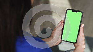 Young Woman at Home using with Green Mock-up Screen Smartphone in Vertical Landscape Mode. Girl Using Mobile Phone